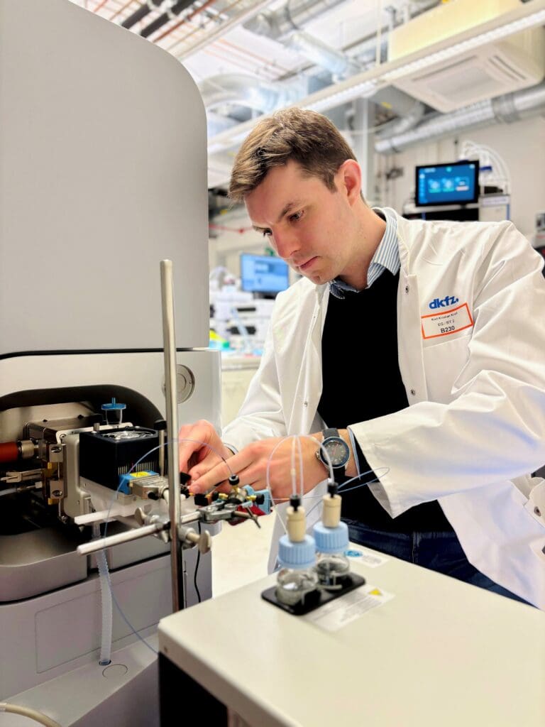 Karl Krull is connecting a viper line from mass spec in a laboratory, he wears a white lab coat